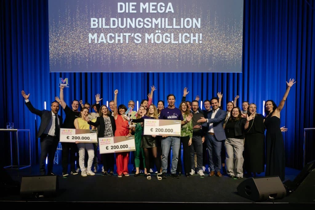 Skills-UP! gewinnt Top-3 MEGA Bildungsmillion 2025 — das Team auf der Bühne mit dem Preischeck